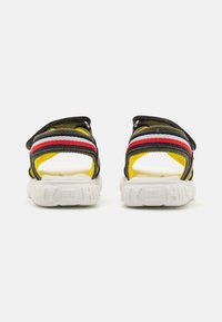 Sport sandaler med en brun tekstiloverdel og flerfargede stripete stropper, hvit såle med teksturerte detaljer og justerbare bakstropper.
