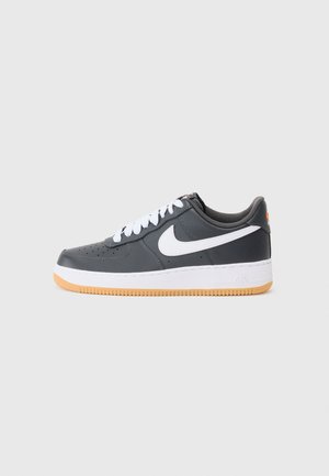 Baskets Nike Air Force 1 gris foncé avec logo swoosh blanc, lacets blancs, semelle intermédiaire blanche et semelle extérieure en gomme sur fond clair.