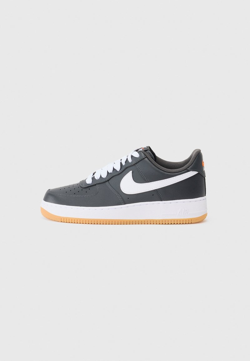 Baskets Nike Air Force 1 gris foncé avec logo swoosh blanc, lacets blancs, semelle intermédiaire blanche et semelle extérieure en gomme sur fond clair.