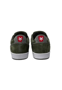 Green suede sneakers with a white rubber sole, featuring grey accents and a red logo patch on the heel. Smooth texture and low-profile design.
