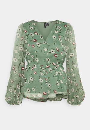 Grüne Blumenbluse mit langen, durchsichtigen Puffärmeln, V-Ausschnitt, Knopfleiste vorne und leicht ausgestellter Taille.