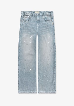 Vaqueros de pierna ancha en azul claro con detalles de salpicaduras de pintura, tachuelas metálicas en los bolsillos delanteros y cierre de botón en la cintura.