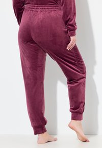 Sametové kalhoty v hluboké burgundské barvě, s elastickým pasem, zúženými nohavicemi a hladkým povrchem.