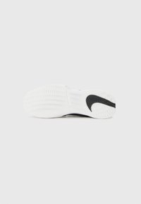 Nike apavi ar pārsvarā baltu gumijas zoli, kas izceļas ar čūsku rakstu un melnu Nike simbolu uz papēža.
