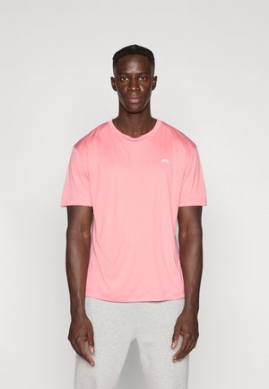 Różowa sportowa koszulka z krótkim rękawem z materiału odprowadzającego wilgoć, z okrągłym dekoltem i małym białym logo na piersi.