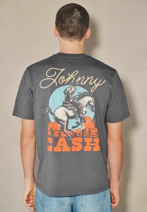 Gray cotton t-shirt featuring a back design with a cowboy riding a horse against a blue circle and orange landscape, labeled "Johnny Cash."