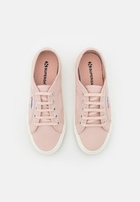 Paire de baskets à lacets en toile rose clair avec semelles en caoutchouc blanches et étiquette de la marque Superga sur le côté, vue de dessus.