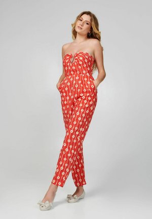 Mono rojo sin tirantes con un patrón floral blanco y líneas verticales, con un detalle de ojal y bolsillos. El material parece ligero y suave.