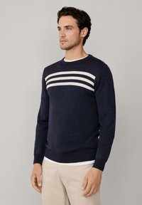 Maglione blu navy realizzato in morbido tessuto a maglia, con strisce bianche orizzontali sulla parte anteriore e scollo rotondo. Maniche e orlo rifiniti.