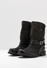 Bottes chevilles en cuir noir avec partie supérieure en tissu à motifs, large sangle avec accent boucle, semelle en caoutchouc, talon bas empilé.