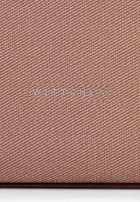 Tessuto rosa testurizzato con un motivo intrecciato, che presenta il nome del marchio in rilievo argentato "WITTCHEN" centrato in fondo.