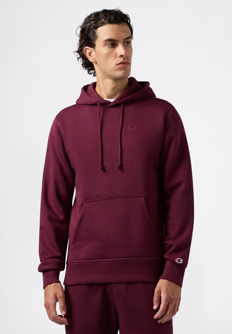 Felpa con cappuccio bordeaux realizzata in tessuto morbido, dotata di tasca a marsupio e un piccolo logo sul petto e sulla manica.