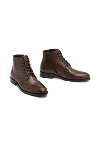 Stivali ankle in pelle marrone con design wingtip, dettagli perforati e lacci. Zip laterale per una facile calzata, suola in gomma per aderenza.