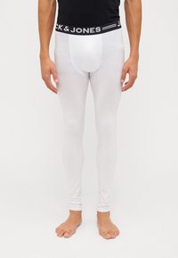 Hvit lang undertøy laget av et mykt materiale, med et svart elastisk livbånd som har teksten "JACK & JONES". Tettsittende design.