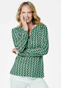 Blusa a maniche lunghe con un motivo geometrico verde, nero e bianco, con scollatura a V e vestibilità rilassata, realizzata in tessuto leggero.