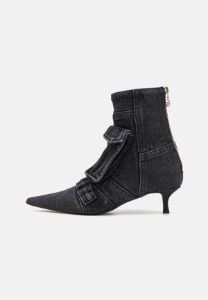 Pointed-toe ankle boot made of black denim with a rounded kitten heel, featuring a side zip and decorative fabric flap accents.