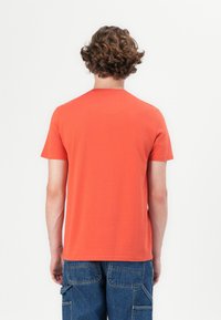 Kortærmet t-shirt i lys orange bomuldsstof med en klassisk rund hals og en afslappet pasform, der viser en glat tekstur og et enkelt design.