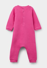 Růžový bavlněný overal s dlouhými rukávy, žebrovanými manžetami a zapínáním na knoflík na zádech. Má jednobarevný design s volným střihem a zakulaceným výstřihem.