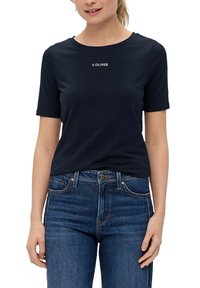 Marineblauw T-shirt met korte mouwen, gemaakt van zachte katoen, met een ronde halslijn en een klein, centraal wit logo, gecombineerd met donkerblauwe spijkerbroek.