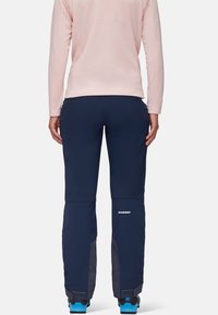 Granatowe spodnie o dopasowanym kroju, wykonane z wytrzymałego materiału, z siateczkowymi panelami na dolnych nogawkach i białym logo z boku.