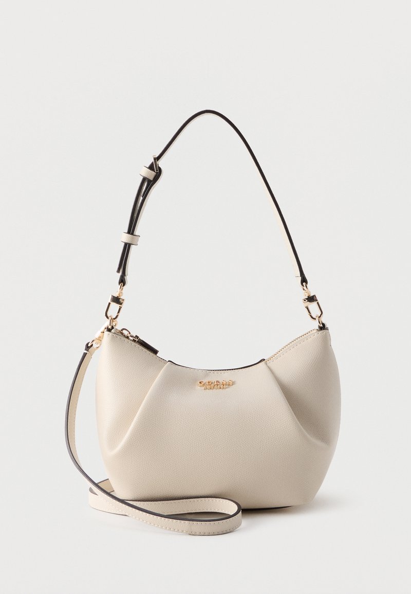 Petit sac à main en cuir blanc cassé avec logo doré, bandoulière ajustable et sangle longue supplémentaire enroulée à la base.