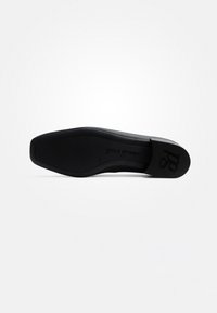 Černá bota s hladkou, plochou podrážkou, která má zaoblenou špičku a minimalistický design. Logo značky viditelné na podrážce, což naznačuje výrobce.