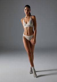 Lys grå ribbet bralette og matchende truse med tynne stropper, glatt tekstur og minimal design, kombinert med lys grå stripete sokker.