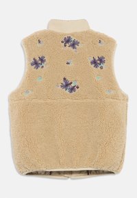 Μπεζ γίβυς με υψηλό γιακά, διακοσμημένος με κεντημένα μωβ και μπλε λουλούδια στην επάνω πλευρά της πλάτης.