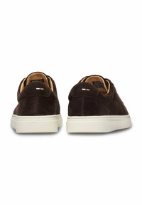 Braune Wildledersneaker mit einem flachen Design, weißen Gummisohlen und minimalen Details an der Ferse. Weicher Stoff mit einem Futter für den Innenbereich.