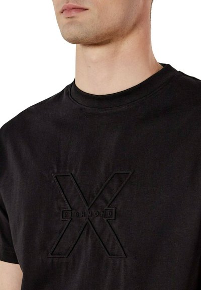 T-shirt in cotone nero con logo ricamato testurizzato di colore nero a forma di "X" al centro, con scollo girocollo.