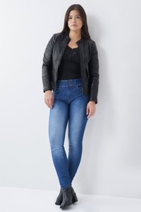 Chaqueta de cuero negra, blusa de encaje, pantalones ajustados índigo de cintura alta y botas negras de tobillo, de pie contra un fondo claro.