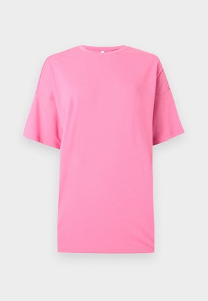 Lys rosa, oversized T-skjorte med korte ermer og rund hals, med fallende skuldre på ensfarget lys grå bakgrunn.