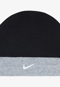 Fekete kötött sapka szürke passzéval. A szürke részen egy kis fehér Nike logó található. Puha tapintású, kerek tetejű.