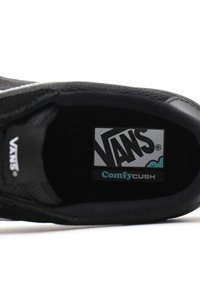 Black Vans sneaker with a textured textile interior, featuring a logo label and "ComfyCUSH" branding in contrasting colors.