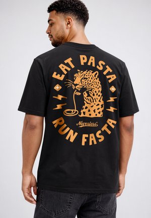 Man wearing black shirt with orange leopard graphic and text "Eat Pasta Run Fasta" on the back.