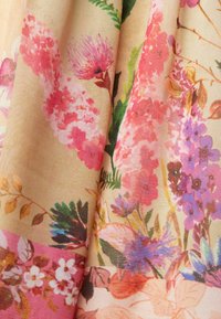 Tissu à motif floral présentant des fleurs roses, violettes et vertes vibrantes sur un fond beige clair avec une finition douce et texturée.