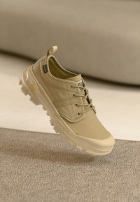 Μπεζ πάνινο αθλητικό παπούτσι με παχύ ελαστικό πέλμα, σχέδιο με κορδόνια, επενδυμένο κολάρο και ετικέτα με το λογότυπο. Διαθέτει υφασμένη επιφάνεια και ανθεκτική ραφή.