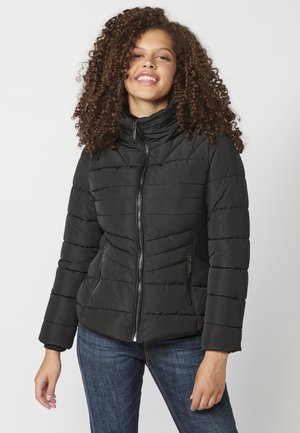 Schwarze Pufferjacke mit hohem Kragen und Reißverschluss, ausgestattet mit horizontalen Nähten, seitlichen Reißverschlusstaschen und gerippten Seitenpaneelen.