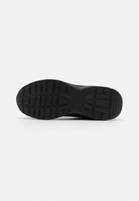 Black athletic shoe sole with deep, rugged tread pattern, made of rubber. Features a flat profile and textured surface for traction.