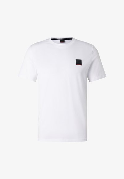 T-shirt blanc à manches courtes et col rond avec un petit écusson rectangulaire noir sur la poitrine gauche.