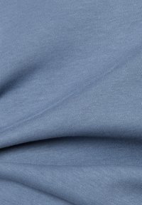 Baumwollstoff in sanftem Blauton mit glatter Textur, der feine Rippungen und subtile Wellen aufweist. Ideal für Bekleidung oder Polsterstoffe.