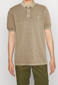 Khaki polo shirt met een zachte textuur, korte mouwen, contrasterende lichte kraag en knopen. Bevat een klein geborduurd logo op de borst.
