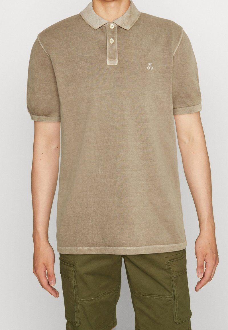 Khaki polo shirt met een zachte textuur, korte mouwen, contrasterende lichte kraag en knopen. Bevat een klein geborduurd logo op de borst.