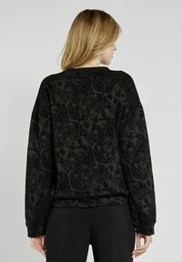 Czarny sweter z wzorem paisley o miękkiej fakturze, z luźnym krojem i długimi rękawami oraz okrągłym dekoltem.