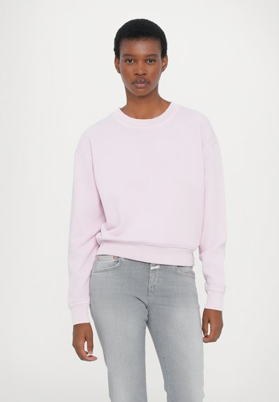 Svetlo roza sweatshirt s krojem okroglega izreza, rebrastimi manšetami in robom; z diskretnim vezanim logotipom spredaj; oblečen z sivo klasiko.