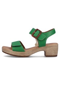 Green leather sandals with adjustable ankle strap, square toe, and a wooden-textured midsole. Features decorative buckle and charm detail.