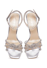 Silberne High-Heelsandalen mit glänzender Oberfläche, quadratischer Zehenpartie und überkreuzten Riemen mit Glitzerdetails für zusätzlichen Flair. Verstellbare Knöchelriemen.
