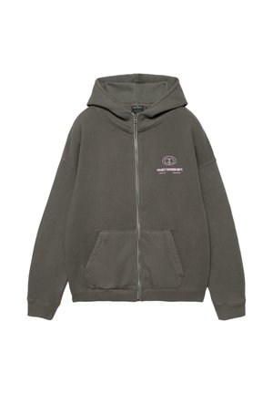 Ciemnozielona bluza na zamek z przednimi kieszeniami oraz małym białym napisem i logo "Project Division Dept." na lewej piersi.