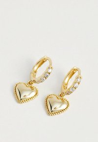 Złote kolczyki koła z małymi przezroczystymi kamieniami szlachetnymi i zwisającymi, polerowanymi charmsami w kształcie serca z ozdobnymi krawędziami.