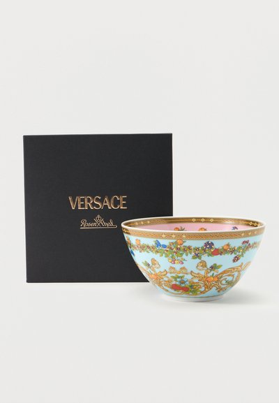 Πορσελάνινο μπολ με χρυσές λεπτομέρειες και πολύχρωμα μοτίβα φρούτων και λουλουδιών, εκτεθειμένο δίπλα σε μαύρο κουτί με την επιγραφή Versace Rosenthal.